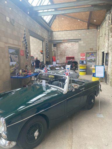 Classic green convertible car displayed in a spacious indoor venue with various exhibits.