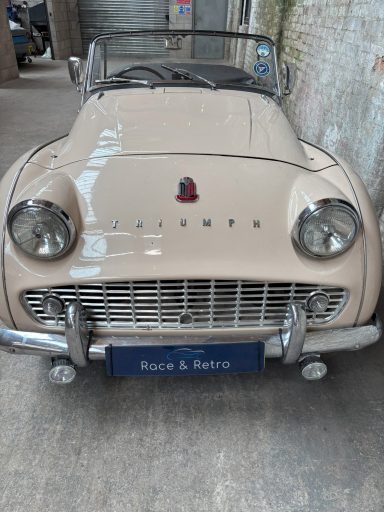 Cream-coloured vintage convertible car parked in a garage.