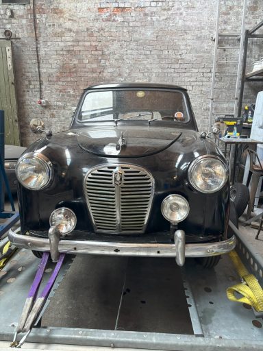 Classic black car in a brick garage with vintage features and chrome detailing.